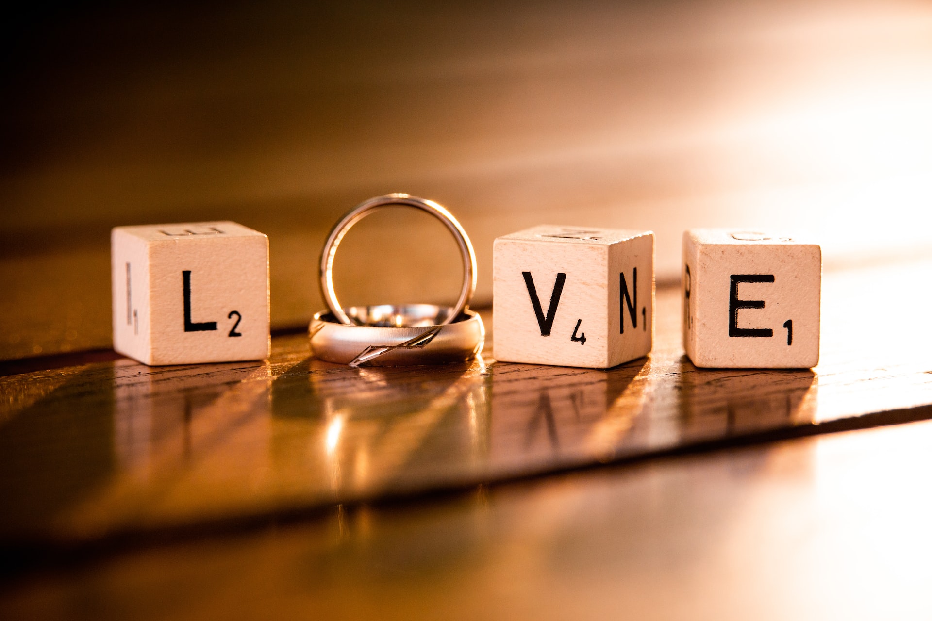 Items on a table create 'Love' - spelled with scrabble-like cubes for the L, V, E, and two rings used to create the O.